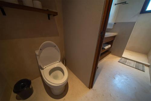a bathroom with a toilet with the seat up at Casa Colibri en Punta Mita in Punta Mita