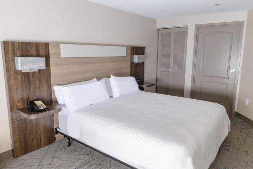 a bedroom with a white bed and a telephone at Holiday Inn Express - Neptune by IHG in Neptune City
