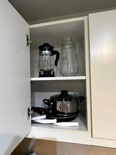 a kitchen cupboard with a pot and a glass appliance at Uptown BGC in Manila