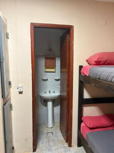 a bathroom with a sink next to a bathroom with two bunk beds at Hostel Park Iguazu in Puerto Iguazú