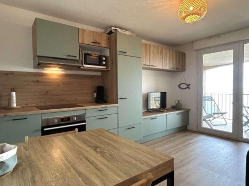 une cuisine avec des placards bleus et une table en bois dans l'établissement Appart 2 pièces 4 couchages BANYULS SUR MER BN120-4206, à Banyuls-sur-Mer