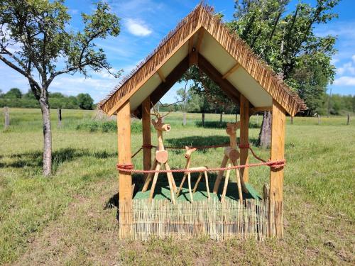 a wooden gazebo with three deer statues in a field at Les cabanes féeriques d'Amoncourt in Amoncourt