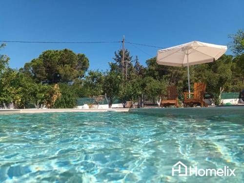 a swimming pool with an umbrella and chairs at Venecia of Mani - Relax in a spa pool in Loukísia