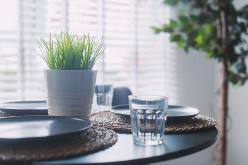 a table with plates and a glass of water and a plant at ComfySleep Apartments in Glasgow