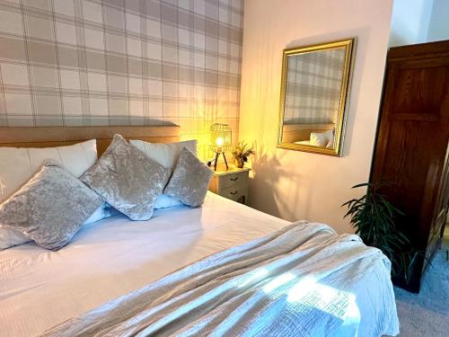a bedroom with a bed with pillows and a mirror at Beechtree Cottage, Cairngorm Suite, Kirkmichael in Blairgowrie