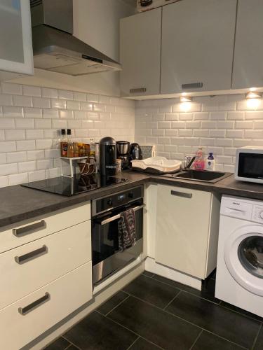 une cuisine avec une cuisinière et une machine à laver dans l'établissement Appartement terrasse proche paris, à Saint-Cloud