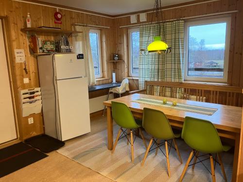 a kitchen with a table and green chairs and a refrigerator at Lugnåsberget Ekohotell in Mariestad