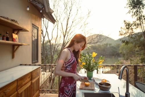 a woman standing in a kitchen preparing food at Quin home, into the forest, close to Noi Bai airport in Phú Hữu