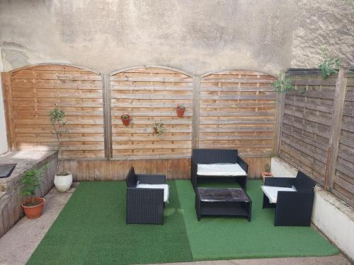 une terrasse avec des tables et des chaises sur un sol verdoyant dans l'établissement Studio tout confort - TV - Wifi, à Dijon