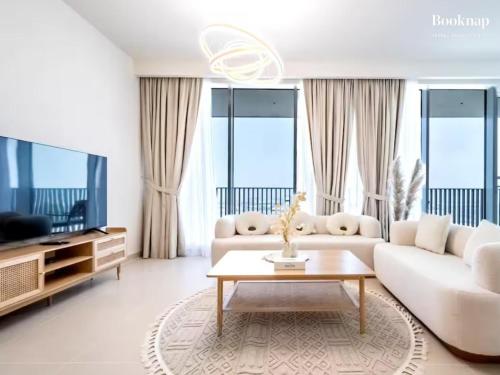 a living room with a white couch and a tv at Lavish 3BR Apartment with Assistant Room in Habour Gate Tower in Dubai