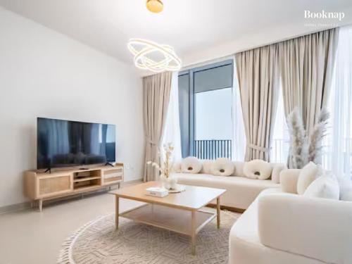 a white living room with a white couch and a tv at Lavish 3BR Apartment with Assistant Room in Habour Gate Tower in Dubai