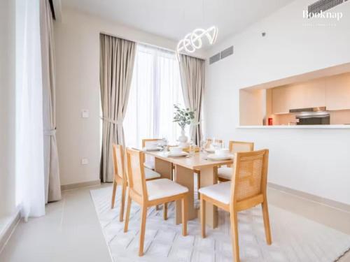 a dining room with a wooden table and chairs at Lavish 3BR Apartment with Assistant Room in Habour Gate Tower in Dubai