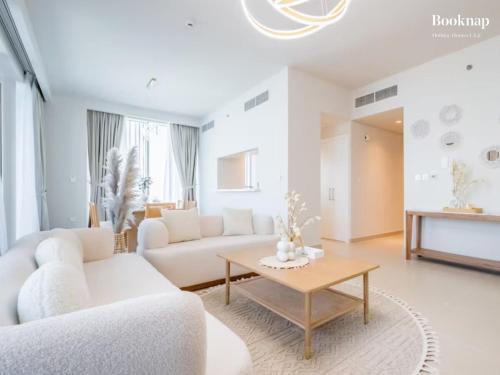 a living room with white furniture and a coffee table at Lavish 3BR Apartment with Assistant Room in Habour Gate Tower in Dubai