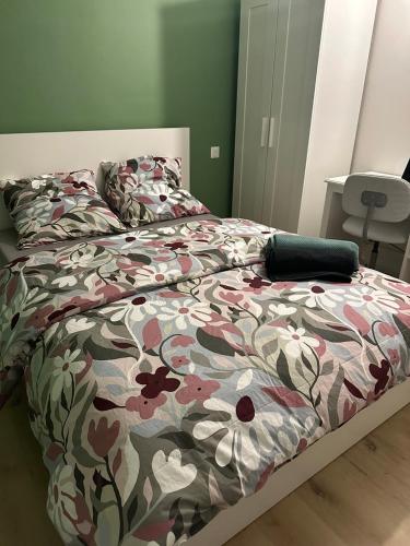 - un lit avec une couette à fleurs dans une chambre dans l'établissement Coup de coeur Grenoblois, à Grenoble