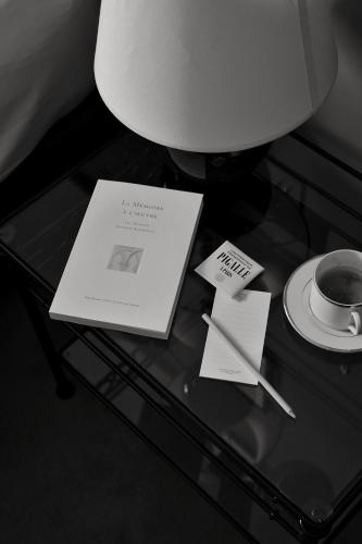 a glass table with cards and a cup of coffee at Hotel Rochechouart - Orso Hotels in Paris