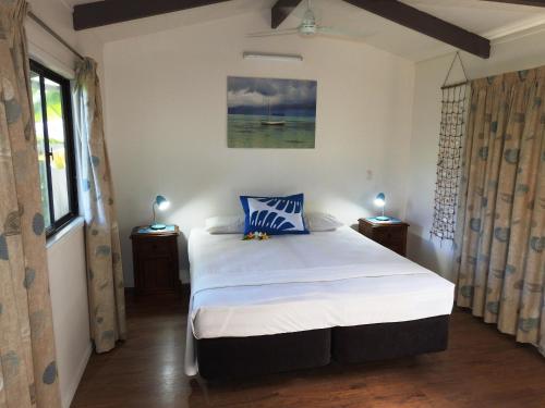 a bedroom with a large white bed with blue pillows at Aremango Guesthouse in Rarotonga