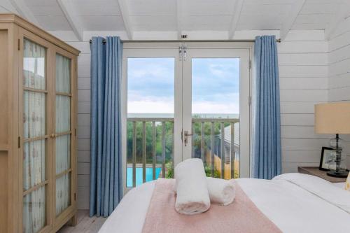 a bedroom with a bed and a large window at Beachfront House w Pool & Steam in West Wittering