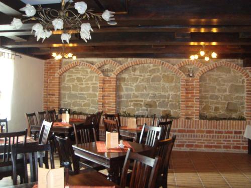 una sala da pranzo con tavoli, sedie e un muro di mattoni di Pension Casa Iurca a Sighetu Marmaţiei