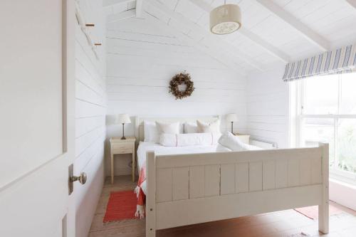 a white bedroom with a bed and a window at Beachfront House w Pool & Steam in West Wittering
