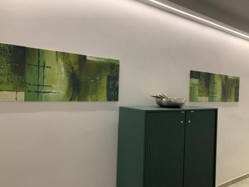 a green cabinet in a room with three paintings at Casa Armonia Apartment Sulmona in Sulmona