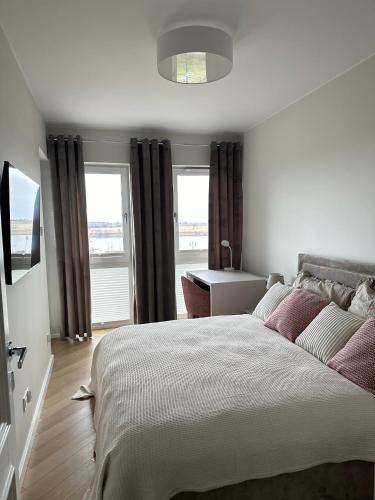 a bedroom with a bed and a desk and windows at Apartament Premium Zamkowa A14 in Tczew