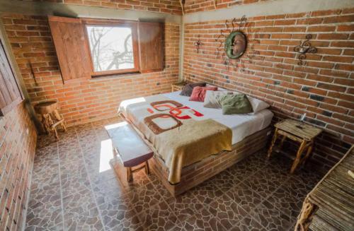 a bedroom with a large bed in a brick wall at Rancho Ecológico Sol De Mayo in Romerillal