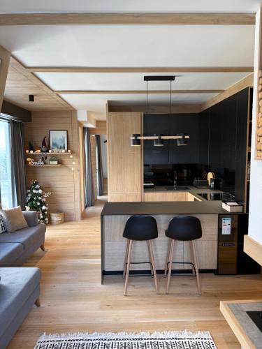a kitchen and living room with a counter and two stools at Ski & Relax Apartment Bjelašnica in Bjelašnica