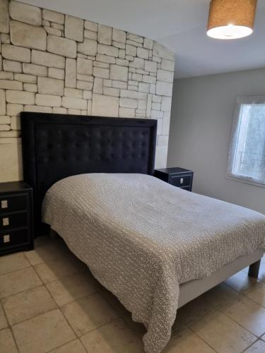 une chambre avec un lit et un mur en pierre dans l'établissement La Bastide, à Châteaurenard