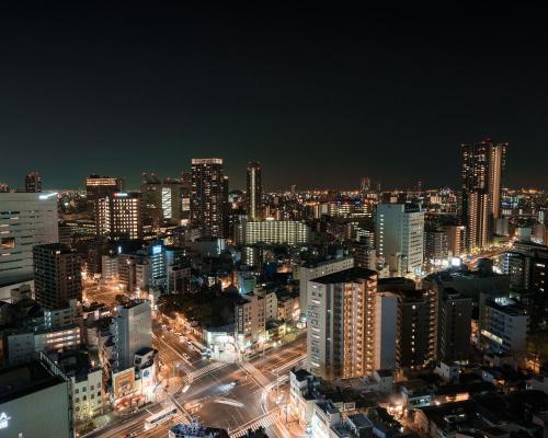 a city lit up at night with buildings at Hotel Hanshin Osaka in Osaka