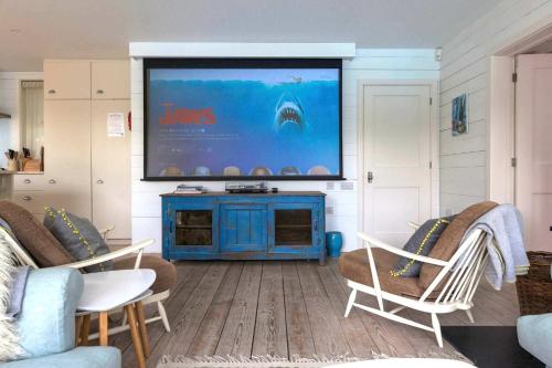 a living room with a flat screen tv on the wall at Beachfront House w Pool & Steam in West Wittering