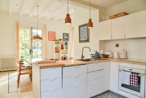 une cuisine avec des armoires blanches et un évier dans l'établissement Maison du golf proche centre, lac et plages, à Soorts-Hossegor