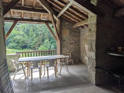 un patio avec une table et des chaises dans un bâtiment dans l'établissement Maison au coeur de la forêt dans le Sidobre - GR36, à Lacrouzette