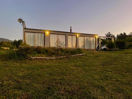 a house with glass windows on a field at Casa de campo in De Cauquenes