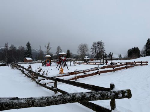 a snow covered field with a fence and a playground at Velflík - ubytování v srdci Krušných hor in Abertamy