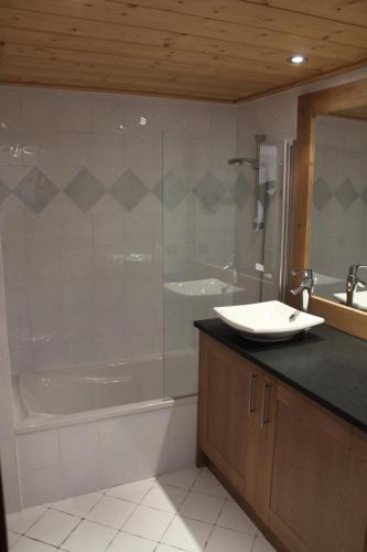 une salle de bain avec une baignoire et un lavabo et une baignoire dans l'établissement Chardons Argentés, à Samoëns