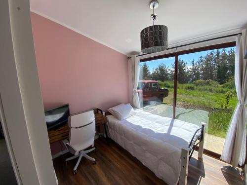 a bedroom with a bed and a desk and a window at Casa de campo in De Cauquenes
