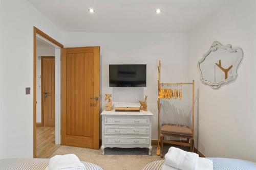a bedroom with a tv and a dresser with a mirror at Ranalegh Court in Saint Columb Minor