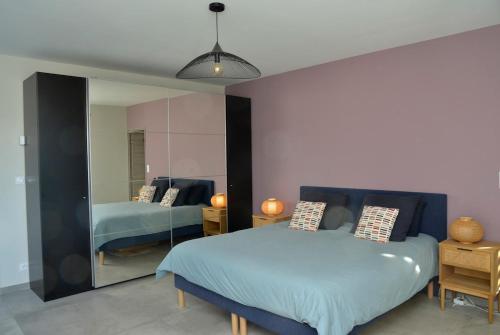 une chambre avec un lit bleu et un miroir dans l'établissement Belle maison avec piscine à débordement chauffée, à Barjac