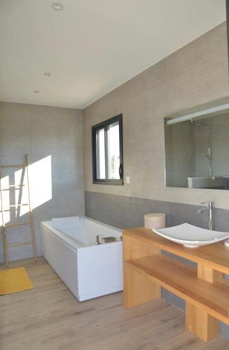 une salle de bain avec une baignoire blanche et un lavabo dans l'établissement Belle maison avec piscine à débordement chauffée, à Barjac