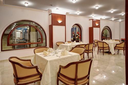 un comedor con mesas y sillas blancas en Hotel Citrin - Adults Only en Brasov