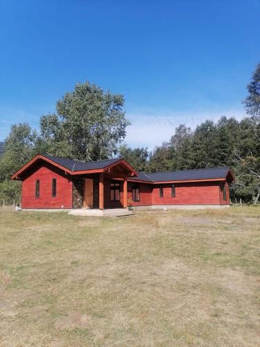 a red barn with a large field in front of it at house in nature in Riñinahue