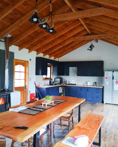 a kitchen with blue cabinets and a large wooden table at house in nature in Riñinahue