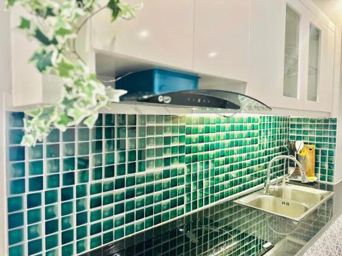 a green tiled kitchen with a sink and a stove at May house Green Bay Garden Hạ Long - near Marina beach in Ha Long
