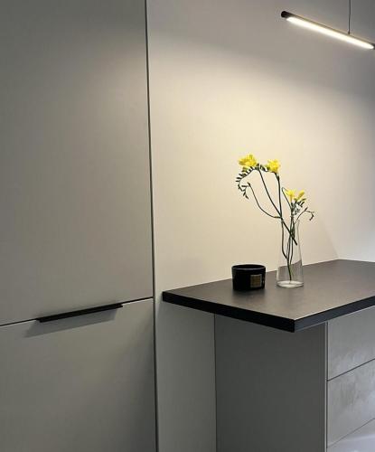 a kitchen with a counter with a vase of flowers at LUX Apartamentai in Marijampolė