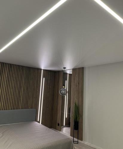 a bedroom with a white bed and a plant at LUX Apartamentai in Marijampolė