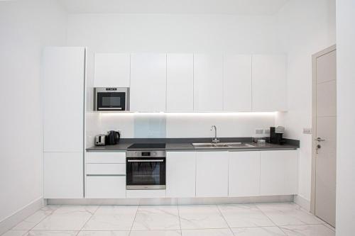a white kitchen with a sink and a microwave at Harley Street Luxury Apartments by City Relay in London