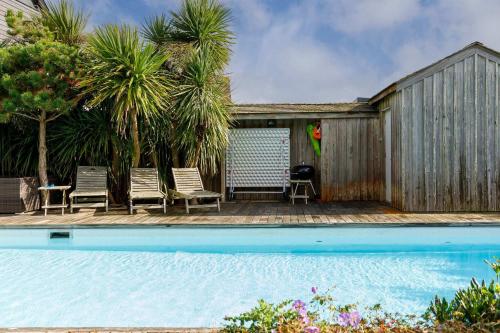 a swimming pool with two chairs and a wooden fence at Beachfront House w Pool & Steam in West Wittering