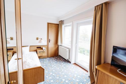 a hotel room with a bed and a tv and a window at Berghotel Hoher Knochen - Ruhe & Natur in Winterberg