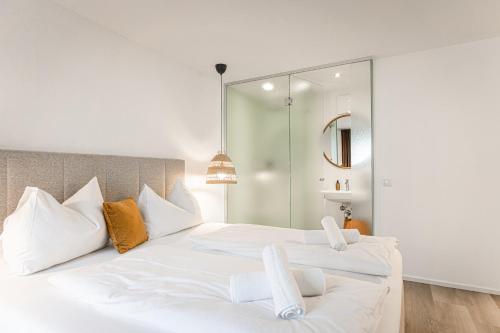 a bedroom with two white beds and a mirror at Lebe`schlitters - Das Ferienapartmenthaus im Zillertal in Schlitters