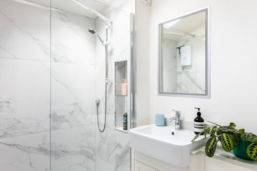 a white bathroom with a shower and a sink at Self contained 1 bed house v near centre, parking in Bath